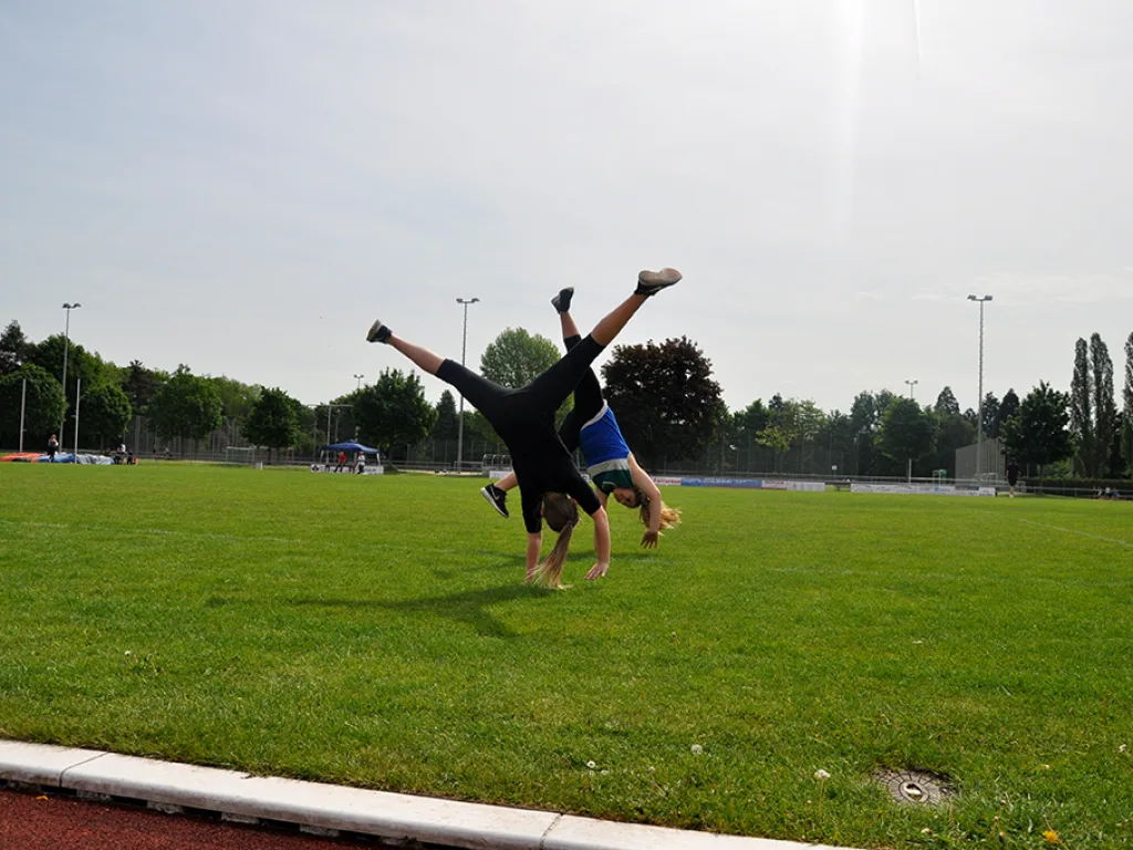 Jugendlicher macht auf dem Rasen einen Handstandüberschlag.